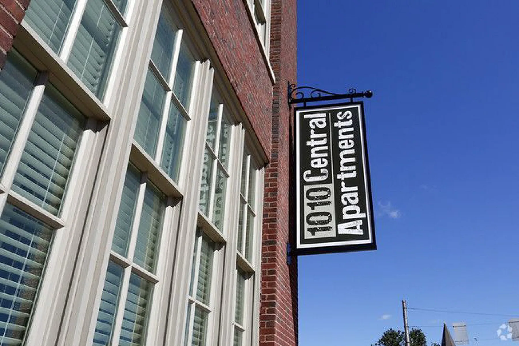 Elegant exterior view of 1010 Central Apartments showcasing vintage brickwork and stylish signage against a clear blue sky.