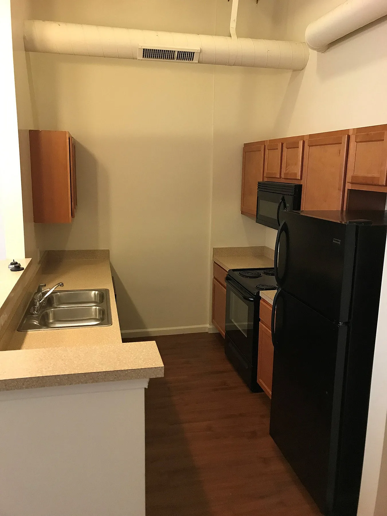 Cozy kitchen with sleek black appliances, elegant wooden cabinetry, and a modern countertop, ideal for culinary delights.