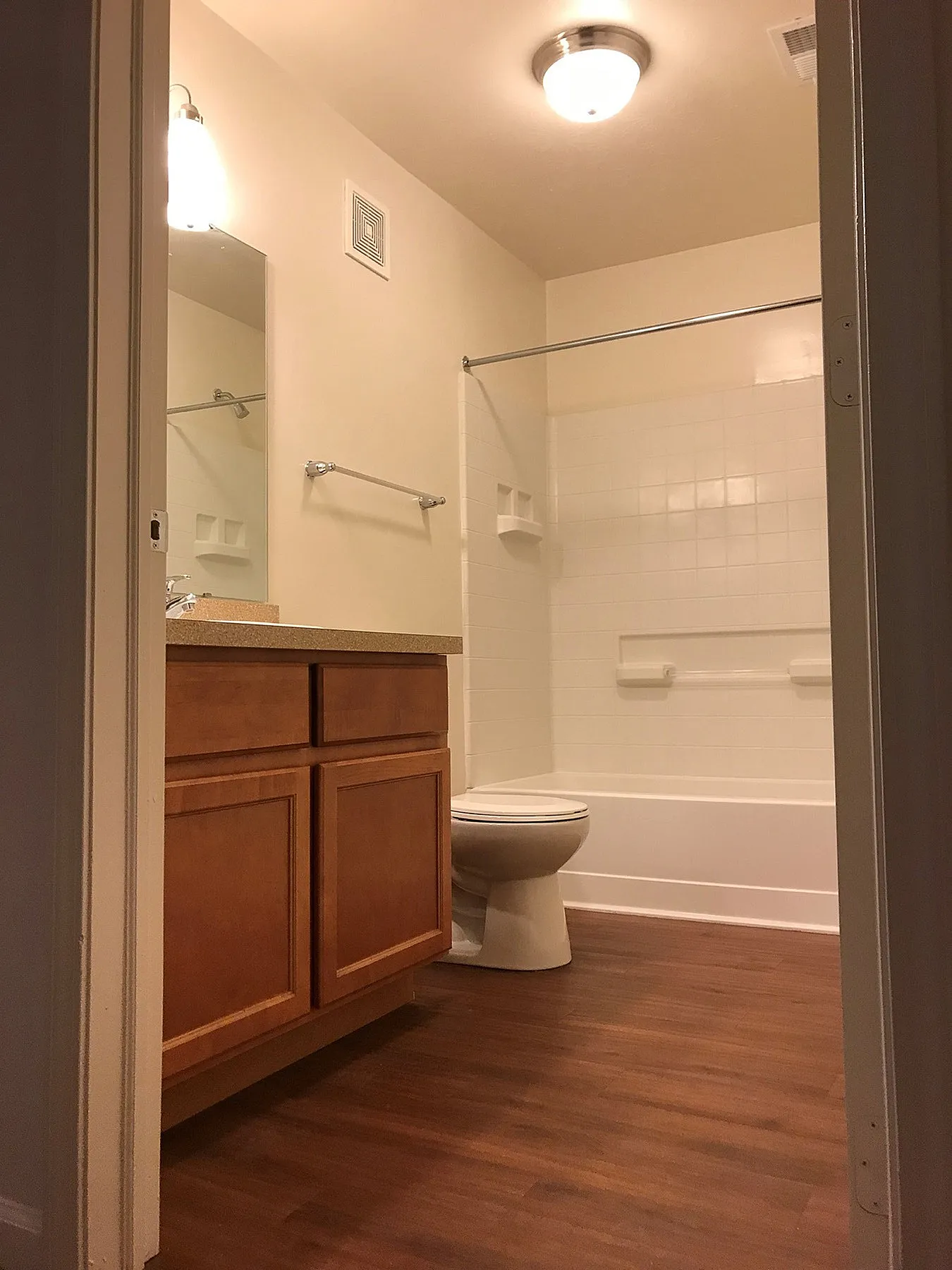 Inviting bathroom with modern lighting, elegant wooden cabinetry, and a pristine bathtub.