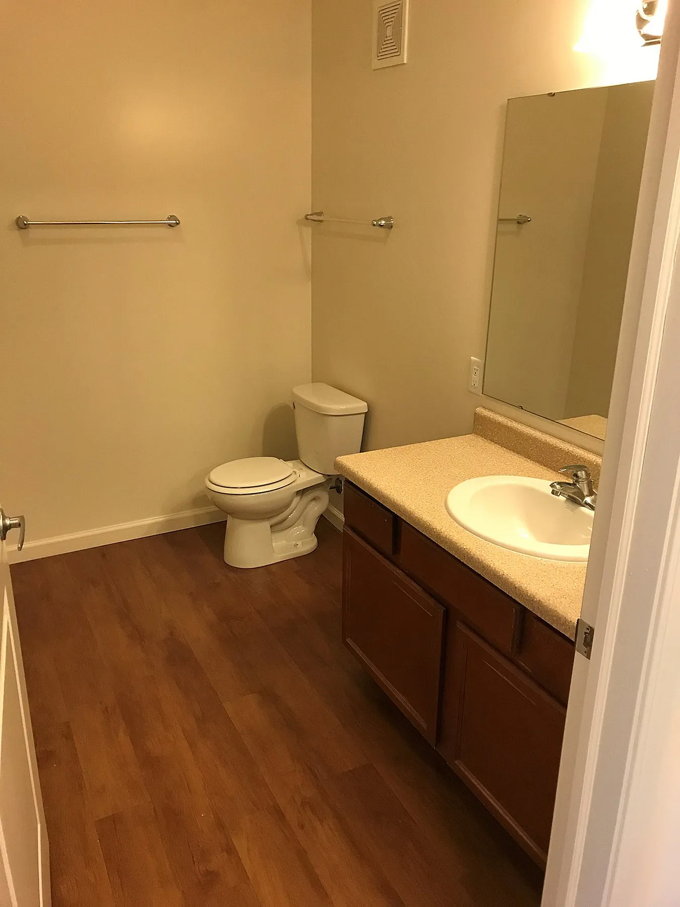 Elegant bathroom featuring warm wood flooring, a sleek countertop with sink, and ample cabinet storage.