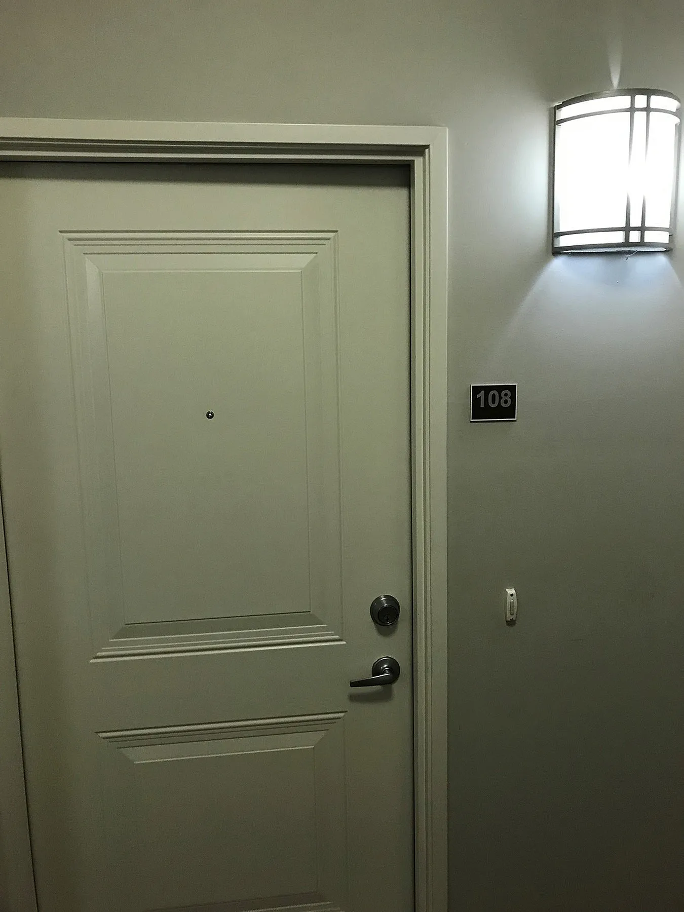Elegant apartment entrance with sleek door and modern lighting above unit 108.