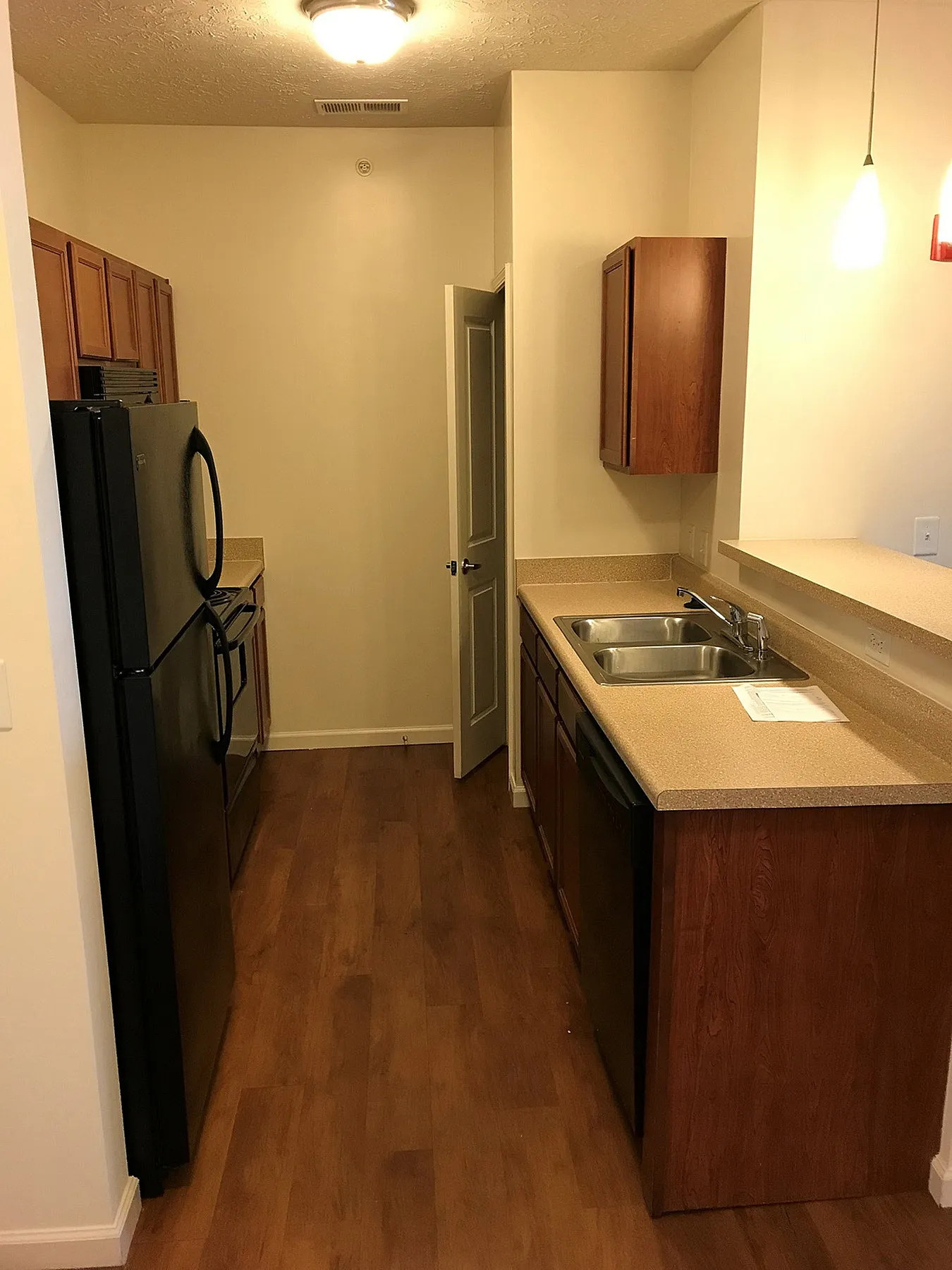 Charming kitchen with warm wood cabinetry, sleek black appliances, and bright modern lighting.
