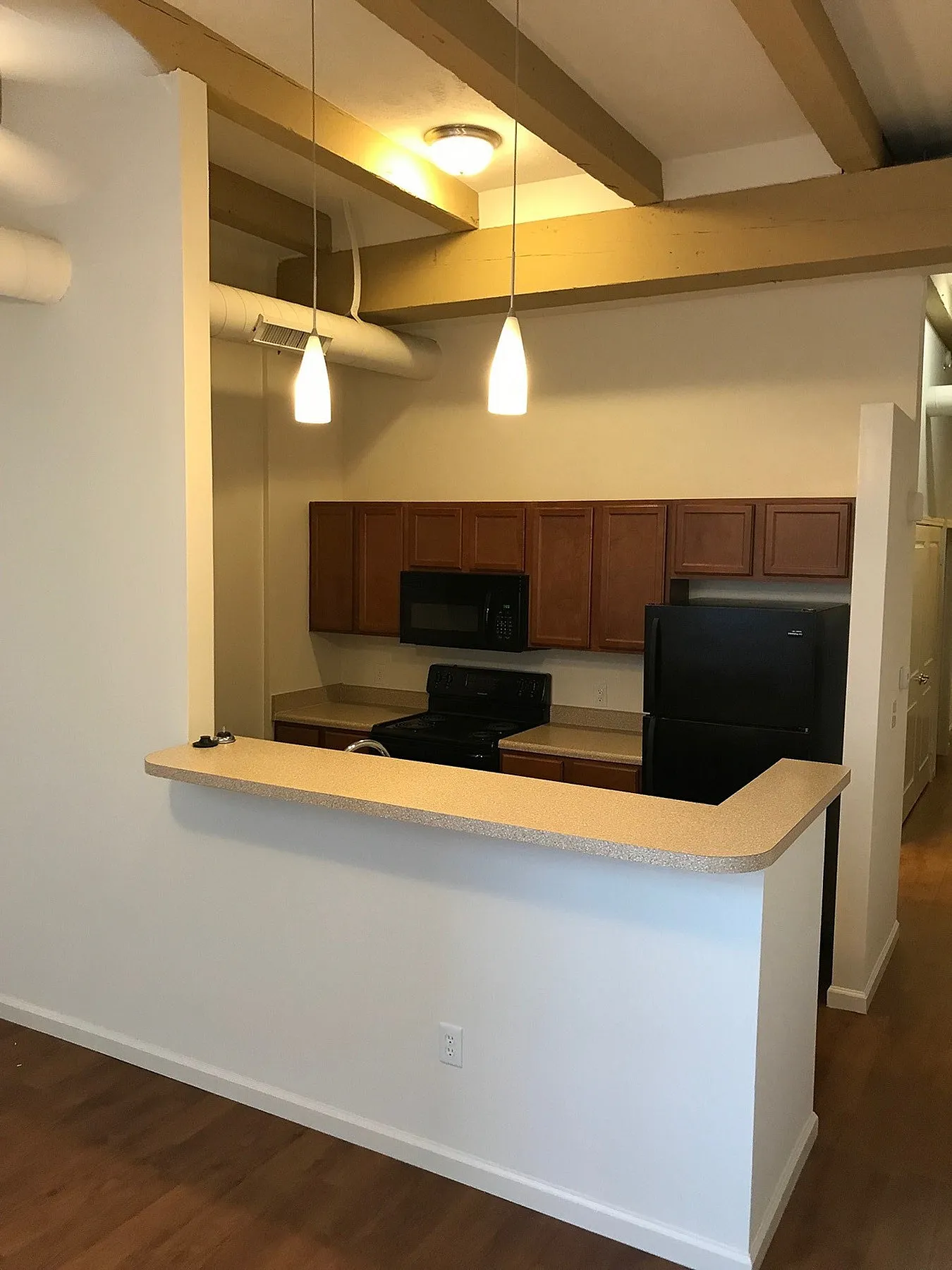 Contemporary kitchen with sleek countertops, pendant lighting, and modern appliances in a loft-style apartment.