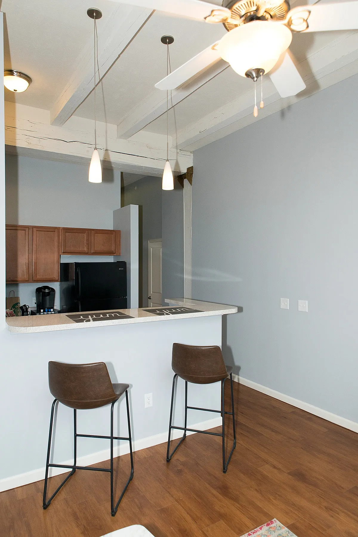 Modern kitchen area with sleek wooden cabinetry, bar seating, and stylish pendant lighting, perfect for entertaining.