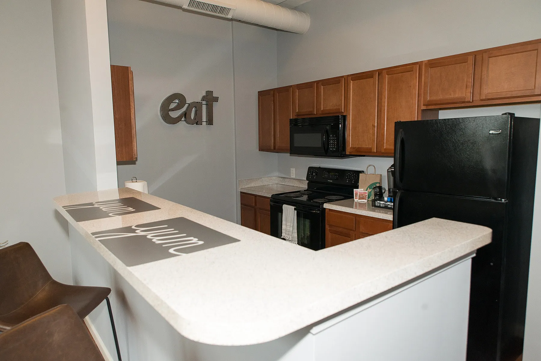 Modern kitchen with sleek countertops, wooden cabinets, and an inviting breakfast bar featuring stylish decor.