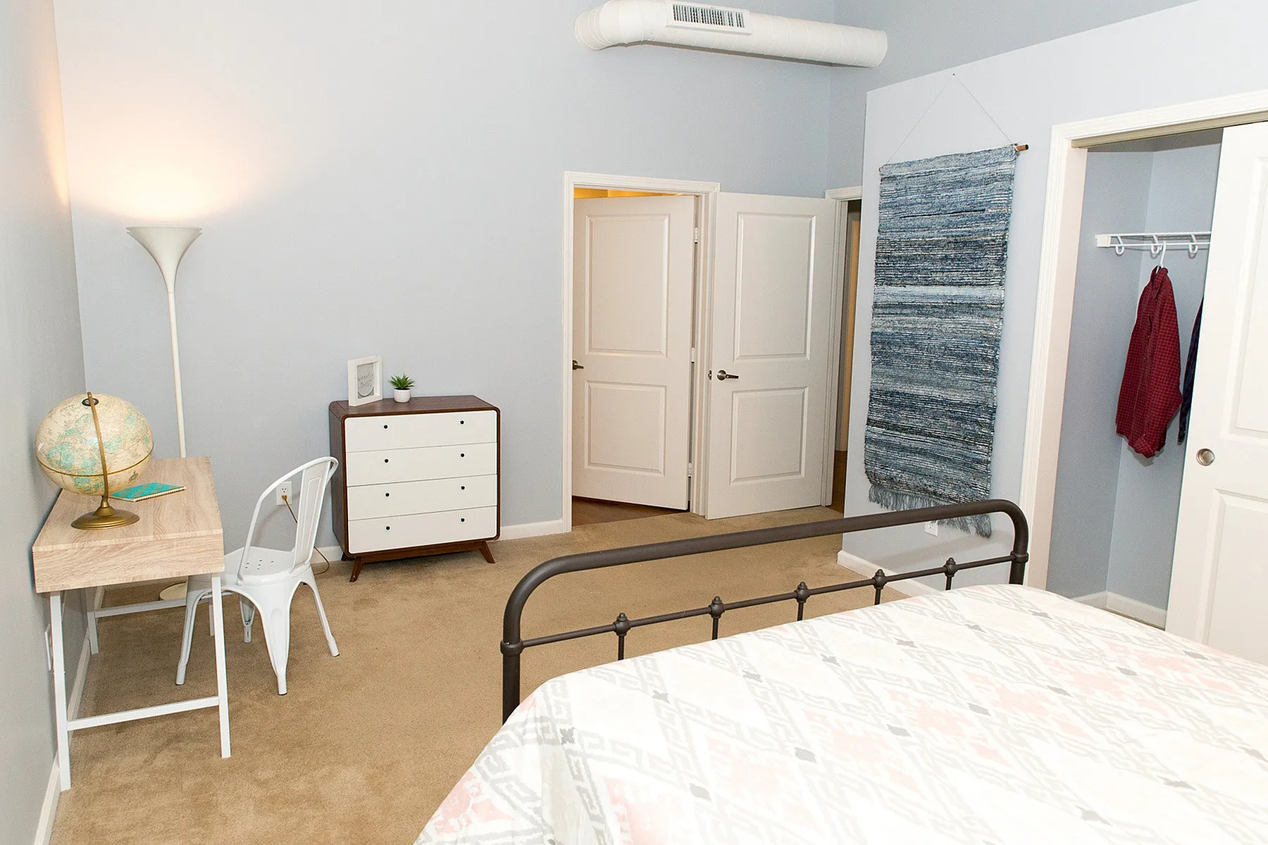 Bright and inviting bedroom with stylish desk area, chic dresser, and cozy decor, perfect for a serene living space.