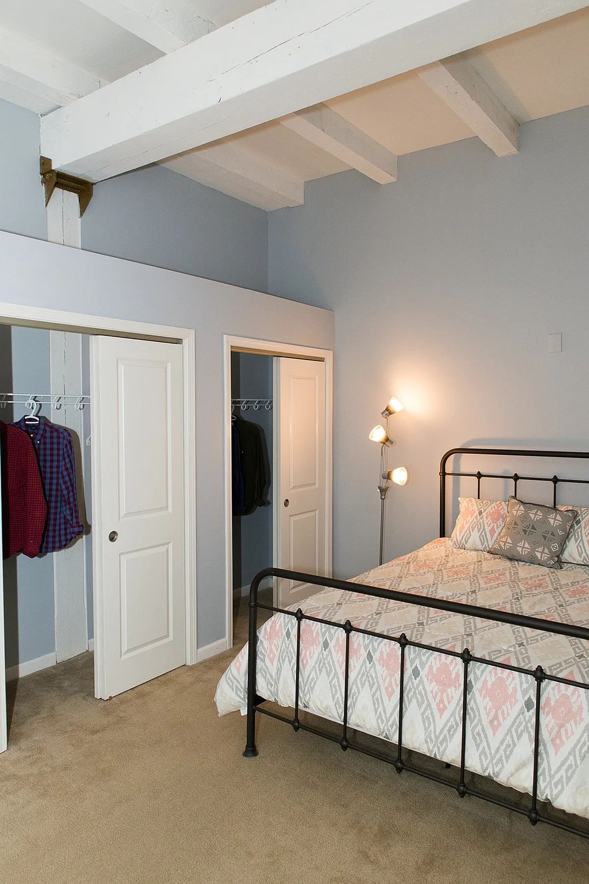 Inviting bedroom with stylish iron bed, cozy lighting, and dual closets offering ample storage space.