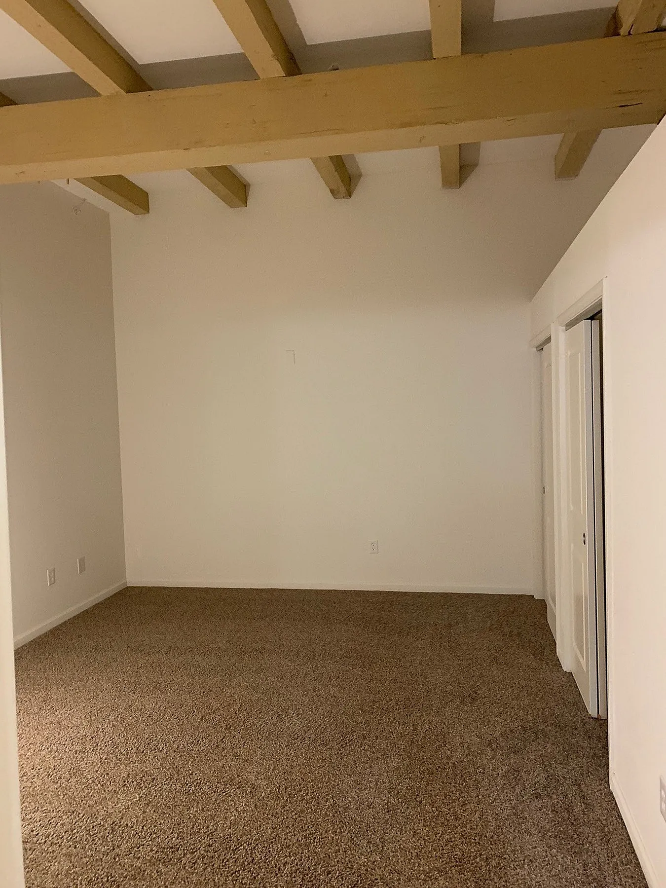 Inviting room with plush carpet flooring and stylish wooden beams, offering a cozy atmosphere for your dream living space.