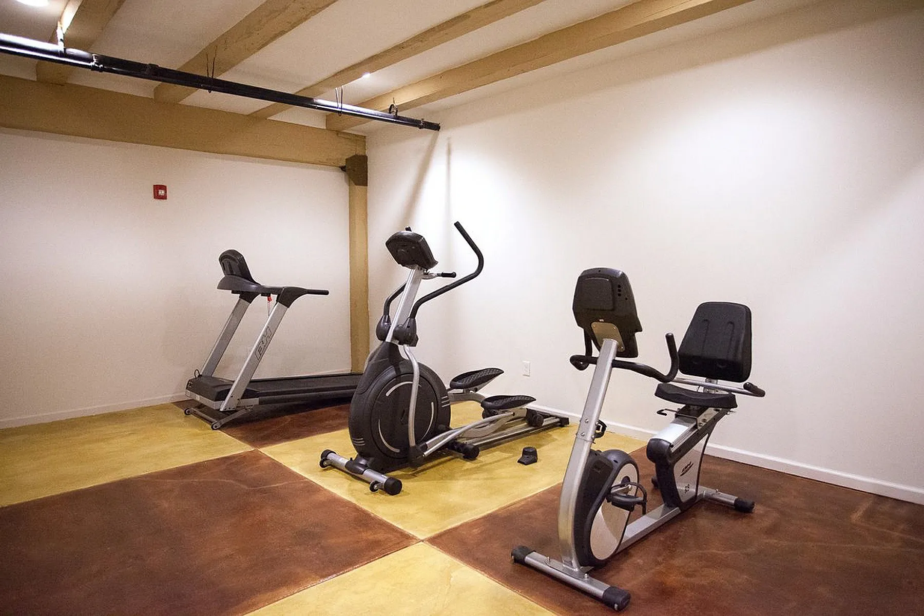 Modern fitness room with treadmill, elliptical, and stationary bike, ideal for home workouts.