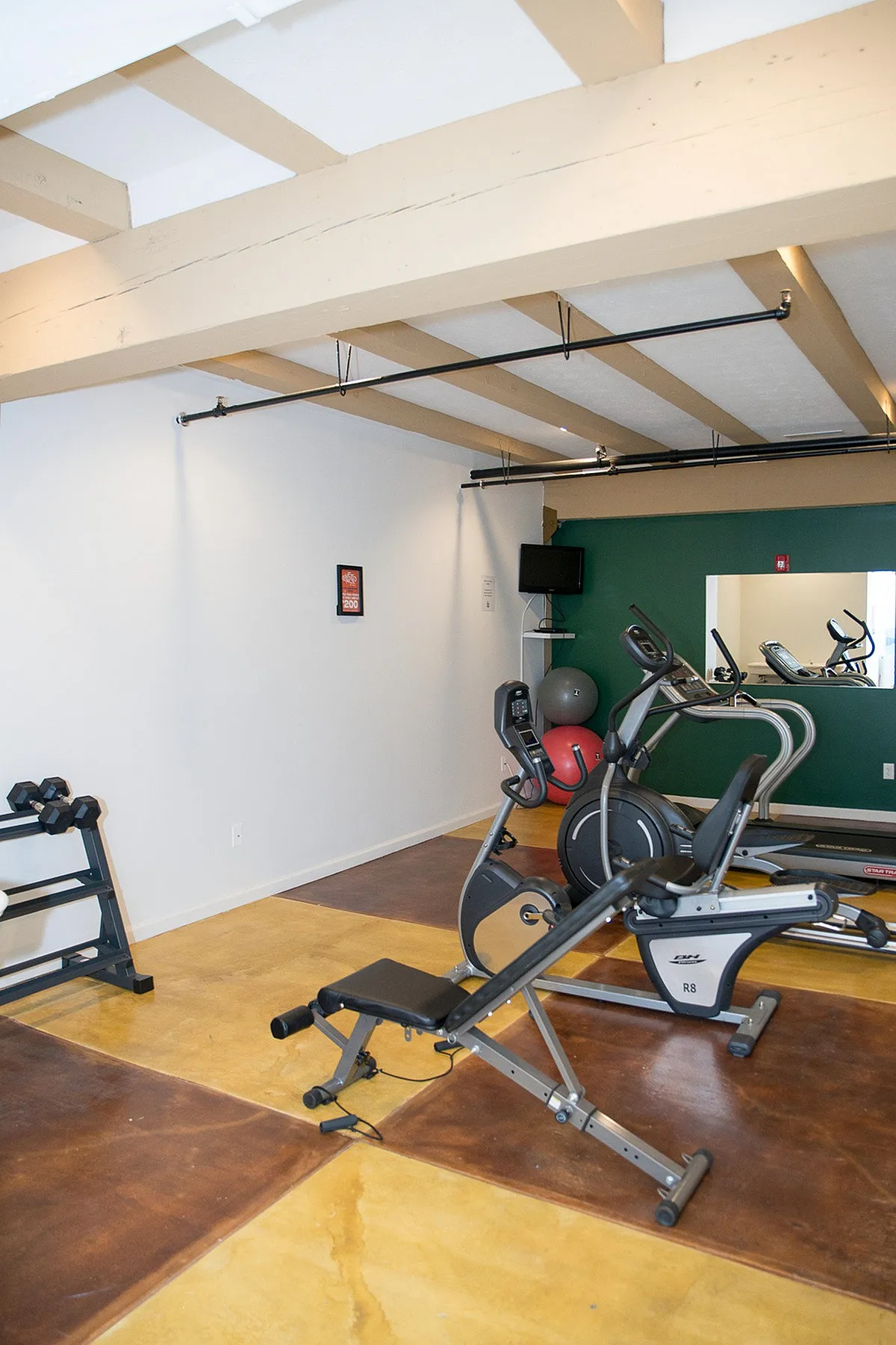 Modern apartment gym featuring state-of-the-art exercise equipment, vibrant flooring, and ample natural light.