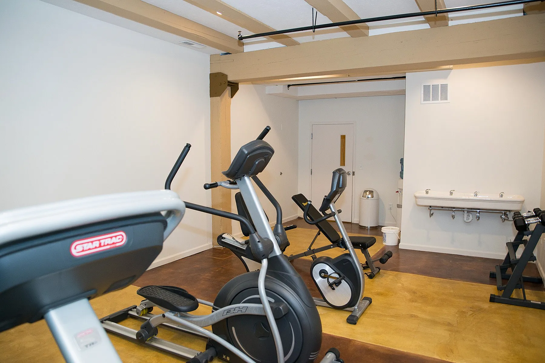 Modern apartment gym room featuring state-of-the-art exercise equipment, sleek elliptical machines, and a minimalist design.