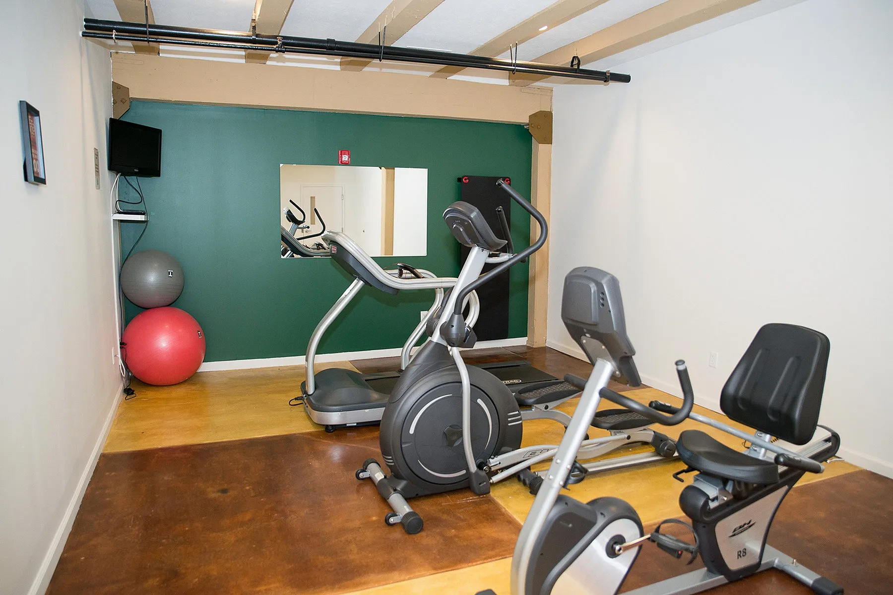 Modern fitness room equipped with elliptical and exercise bike, featuring sleek design and vibrant colors.