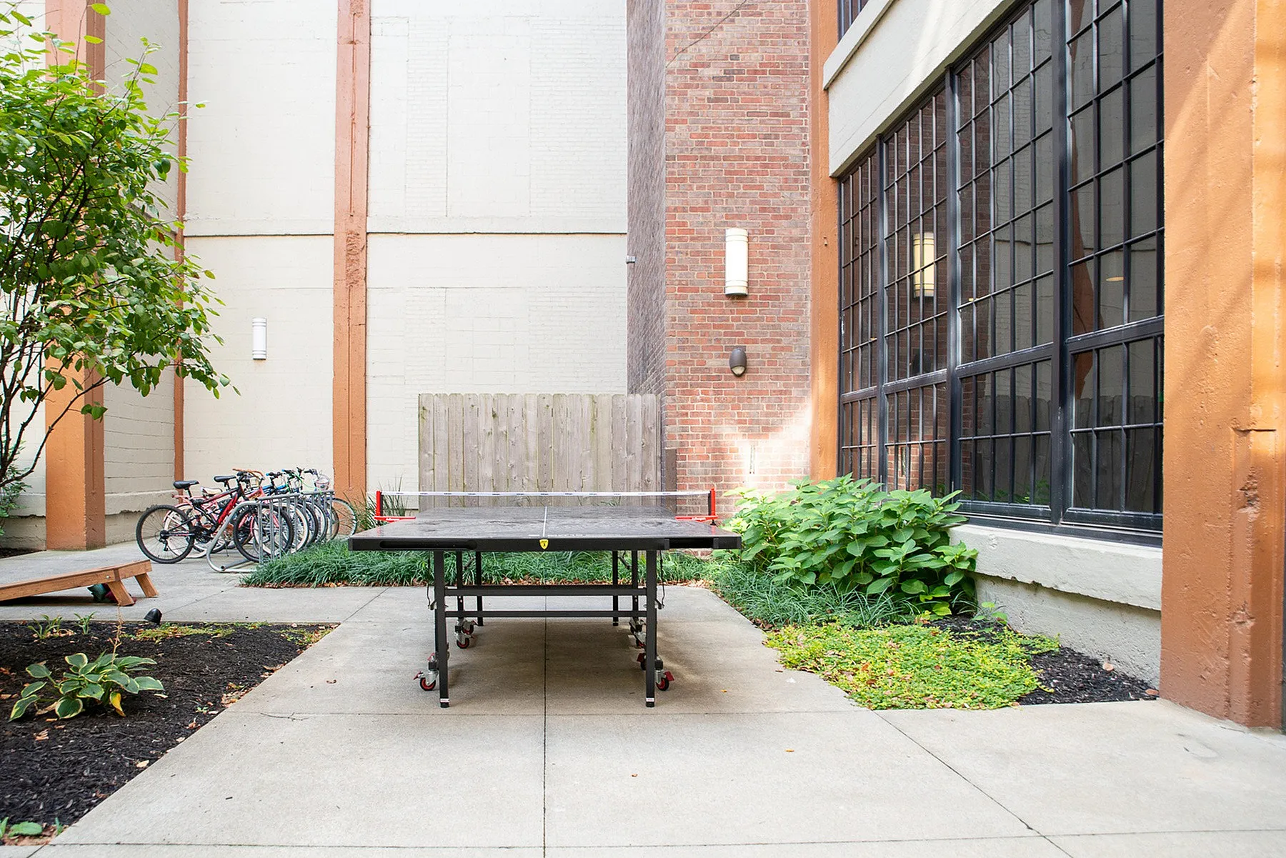 Charming outdoor space featuring a ping pong table, vibrant greenery, and ample bike parking, perfect for relaxation and recreation.