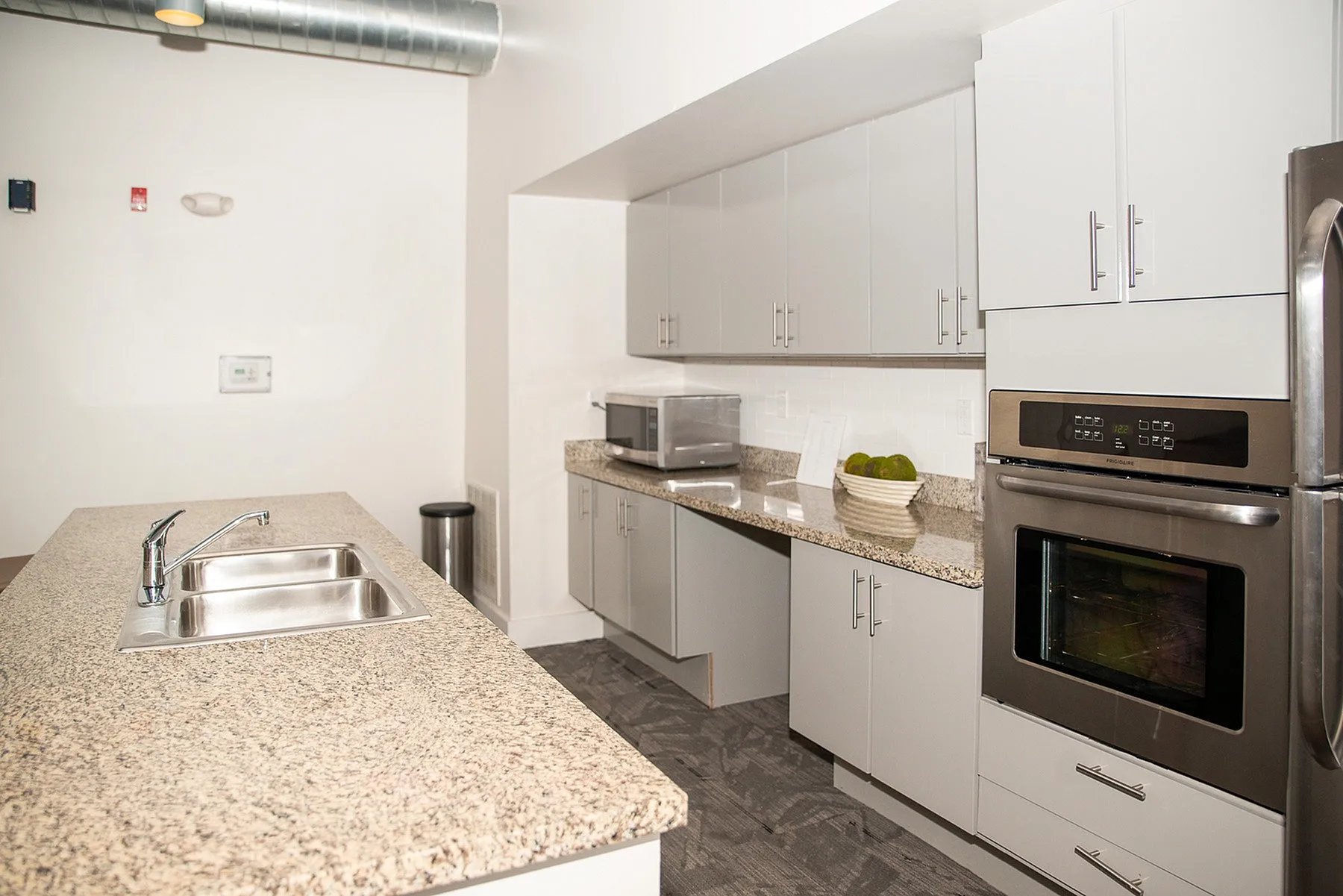 Modern kitchen with sleek gray cabinets, granite countertops, and stainless steel appliances, featuring a stylish island and ample storage.