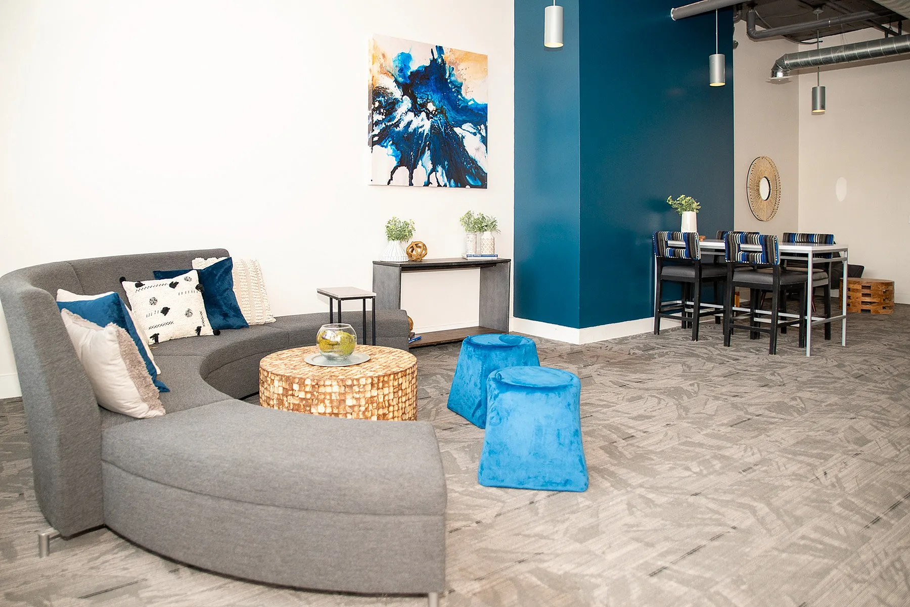 Chic and inviting living area featuring a sleek gray sectional sofa, vibrant blue seating, and modern artwork, perfect for stylish entertaining.