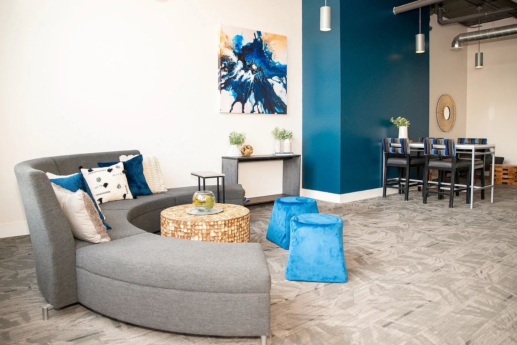 Chic and modern apartment lounge with stylish grey sectional, vibrant blue accents, and contemporary artwork.