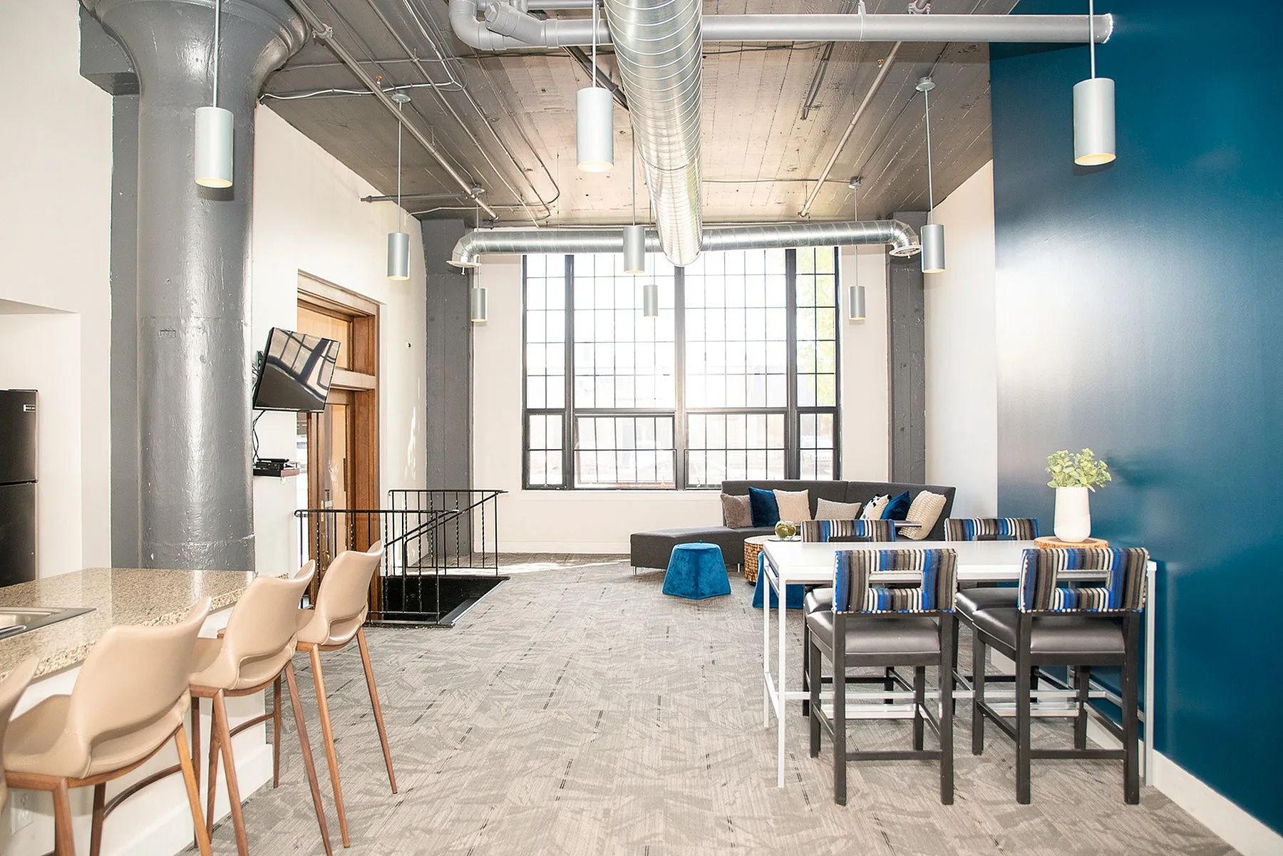 Modern loft space with large windows, stylish furnishings, and industrial charm featuring a cozy living area and sleek dining corner.