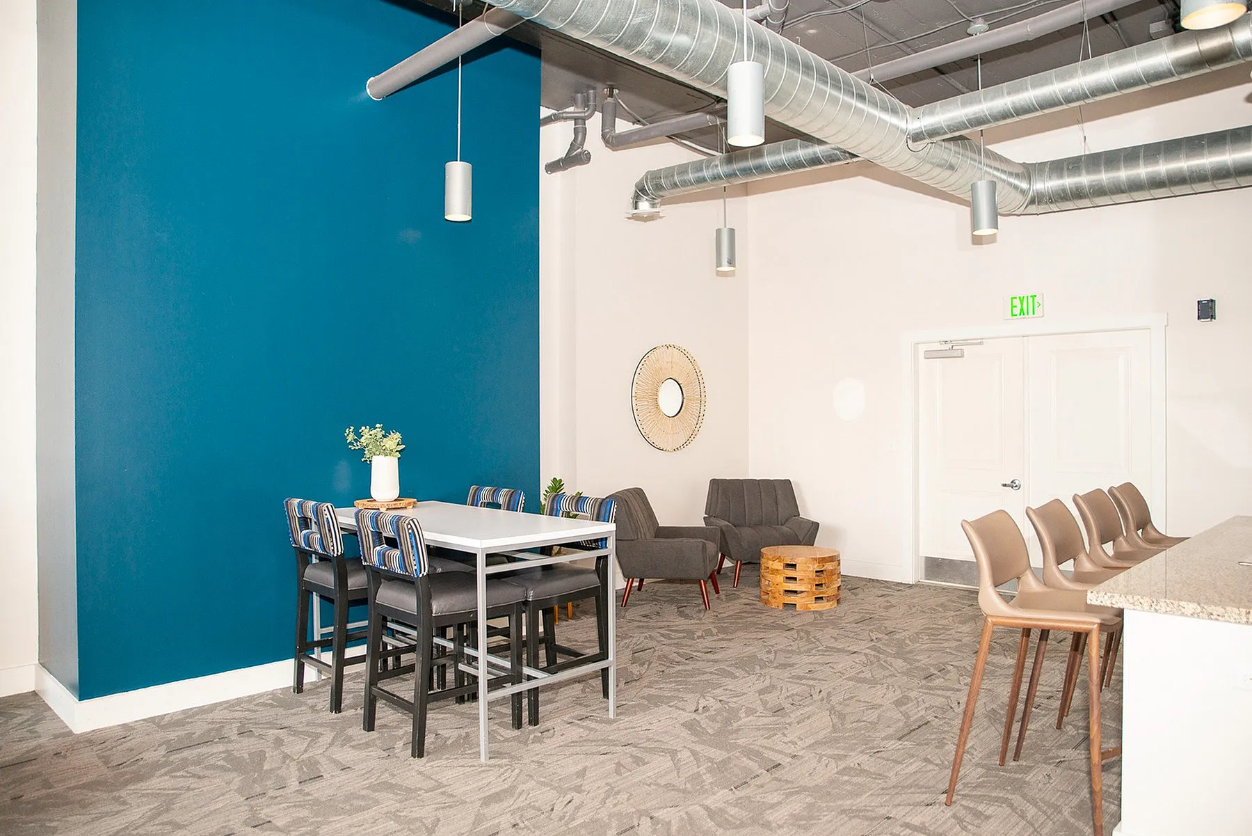Modern communal space with sleek seating, vibrant blue accent wall, and stylish industrial ceiling design.