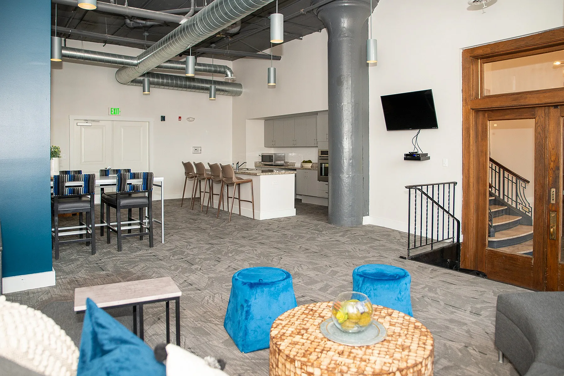 Modern open-concept loft with stylish industrial design, featuring a spacious kitchen with bar seating, contemporary furniture, and unique architectural elements.