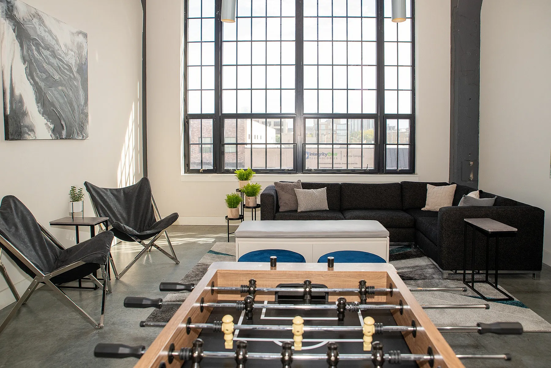 Bright and spacious living room with modern decor, featuring a stylish black sofa, accent chairs, and a large window, perfect for natural light lovers.