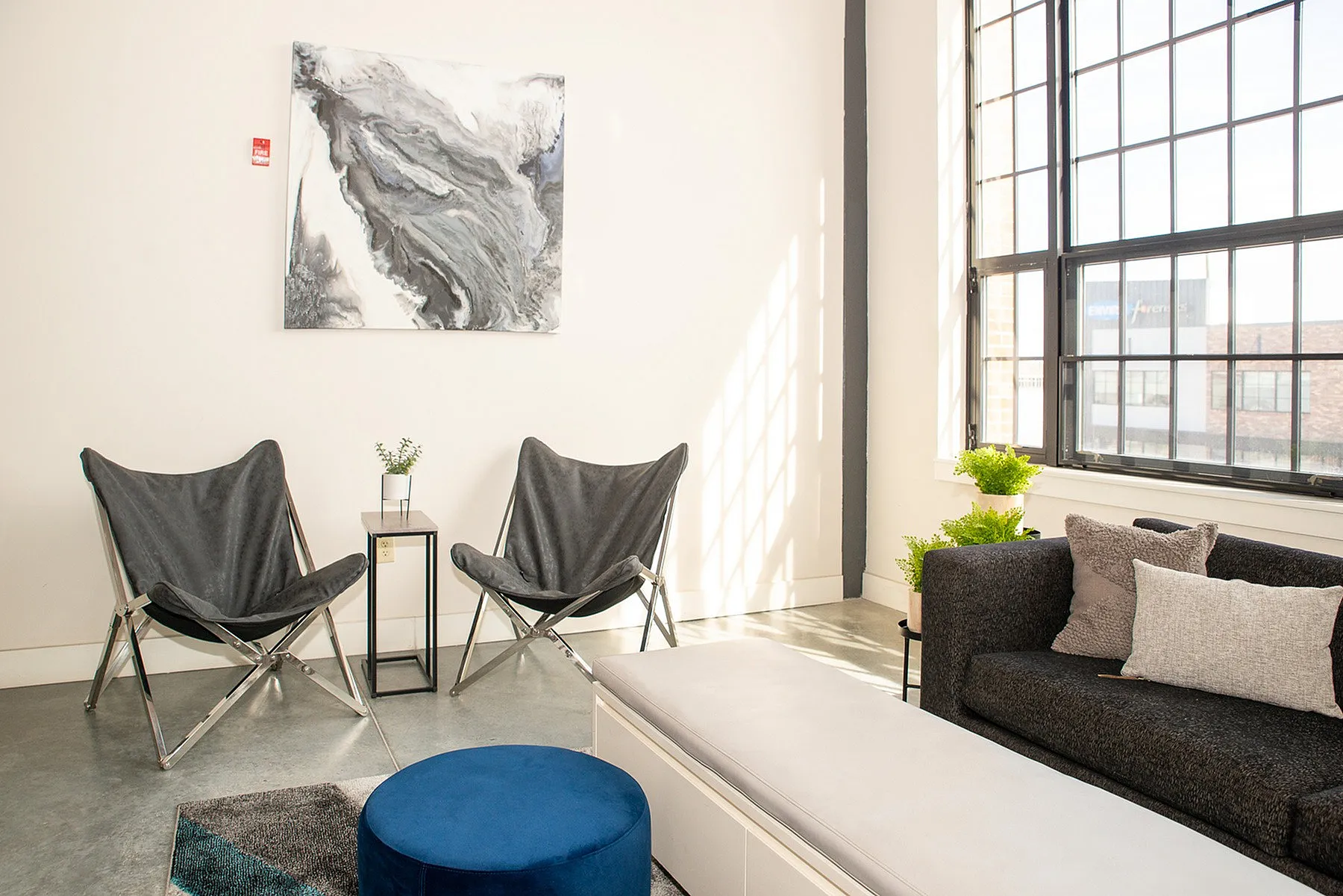 Chic living space with modern seating, large windows, and contemporary art, basking in natural light.