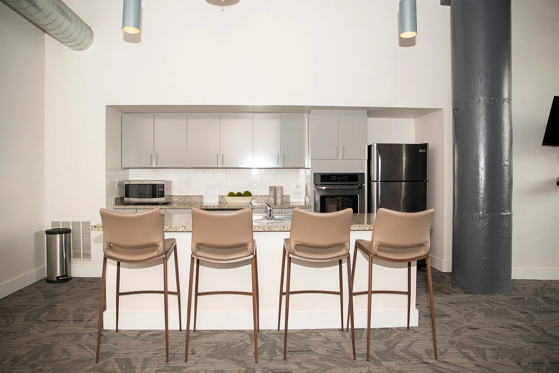 Modern kitchen with sleek gray cabinets, granite countertops, and high bar stools, perfect for entertaining.