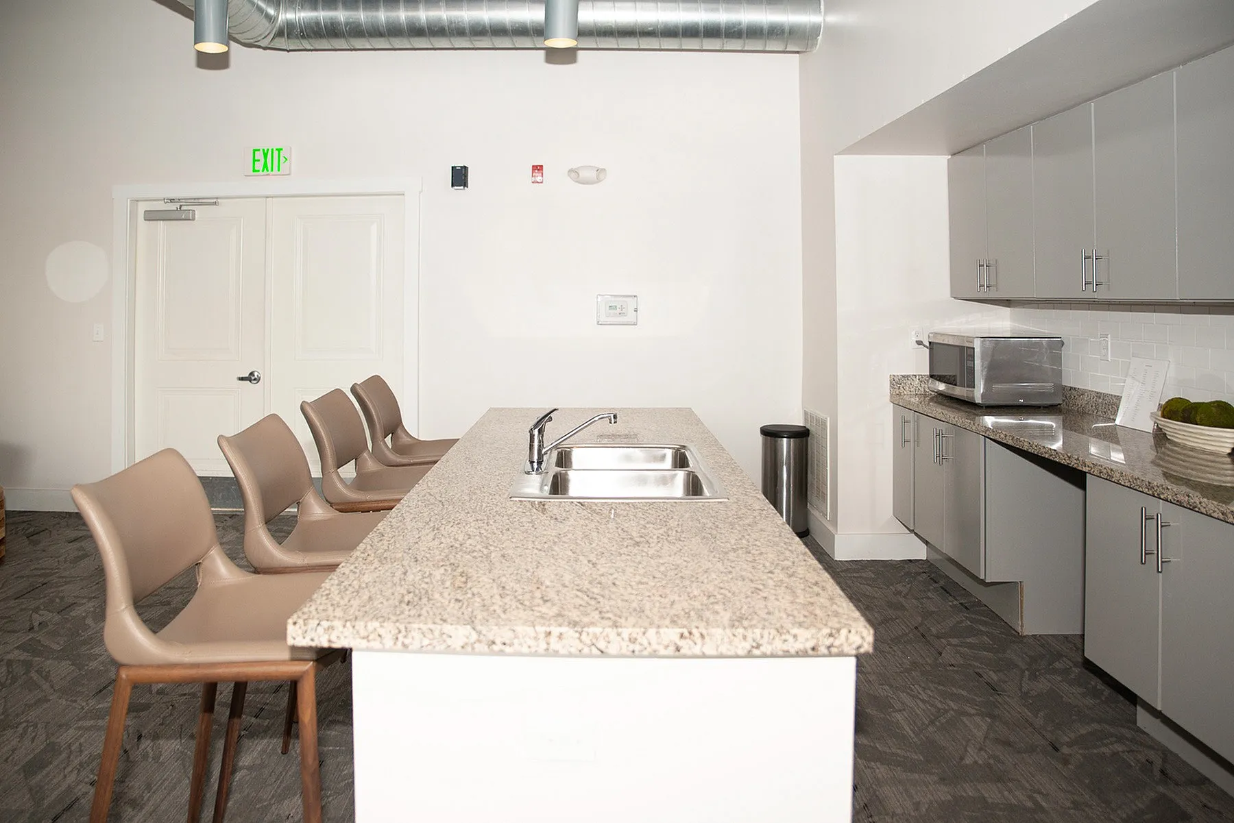 Modern kitchen with elegant granite countertops and a stylish island featuring comfortable bar seating. Sleek grey cabinets and stainless steel appliances enhance the contemporary design.
