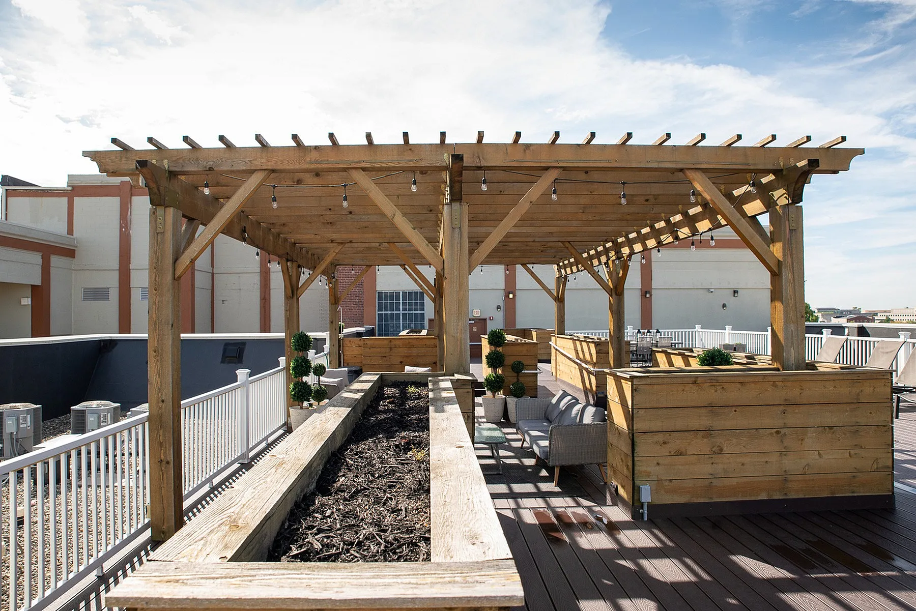 Chic rooftop terrace with stylish wooden pergola, modern seating, and lush planters, offering a perfect urban retreat.