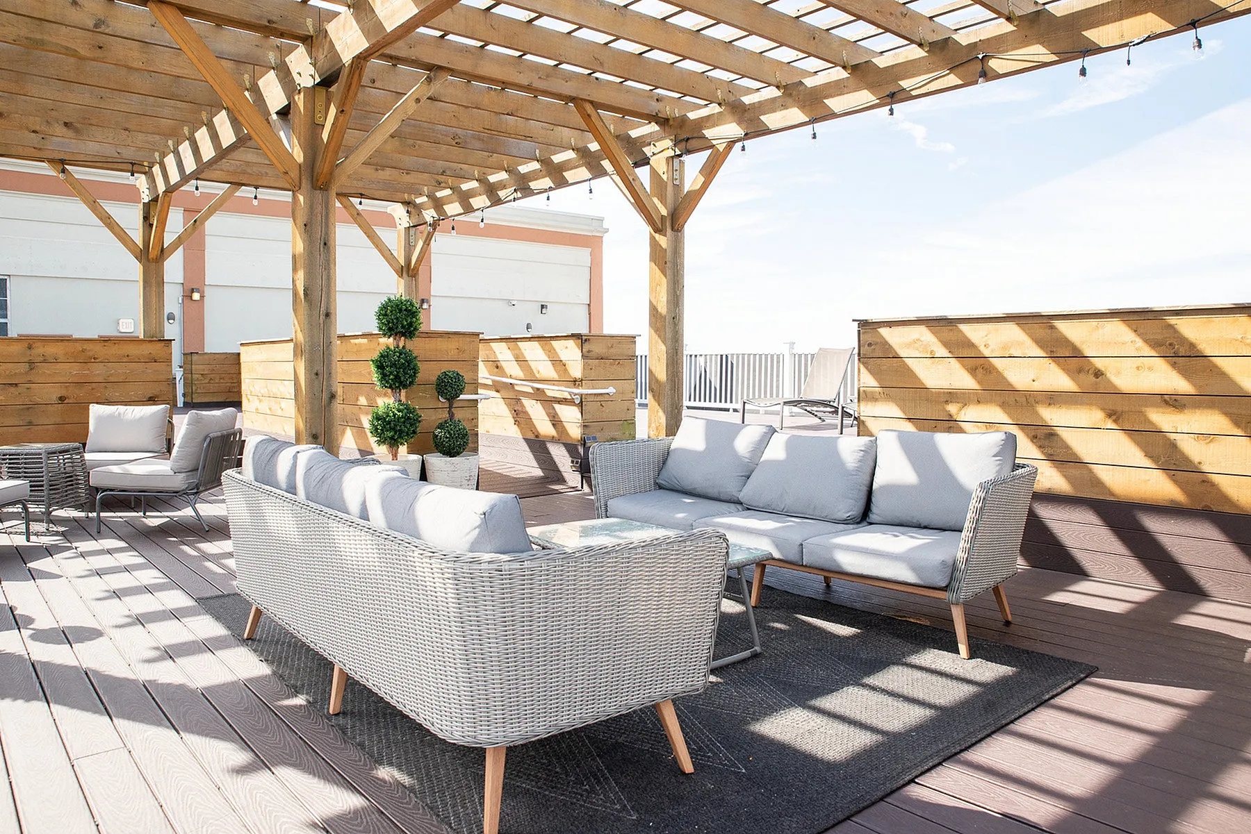 Chic rooftop terrace with stylish wicker seating under a wooden pergola, perfect for relaxing or entertaining.