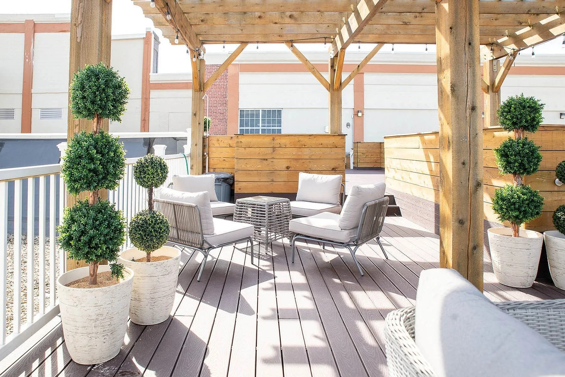 Charming outdoor patio with cozy seating under a stylish pergola, accented by greenery and modern décor.