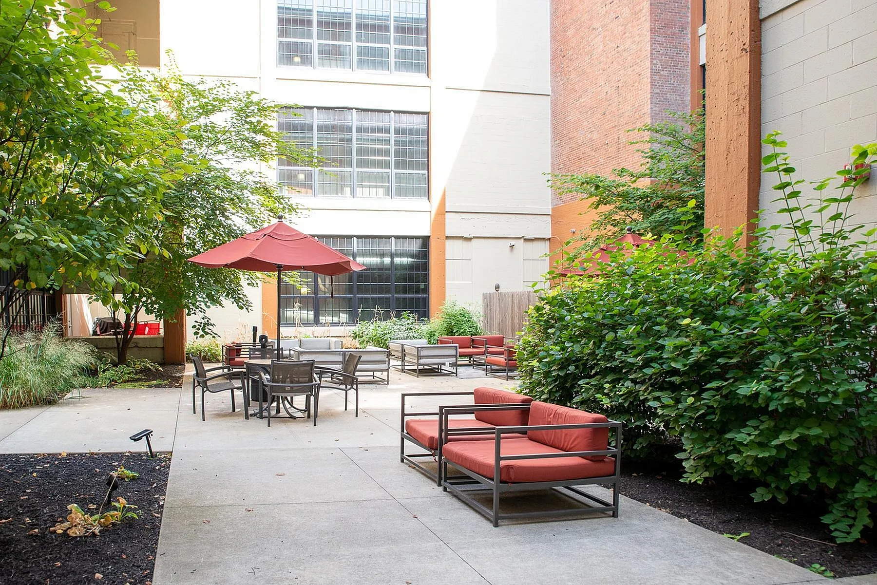 Charming urban courtyard with cozy seating and lush greenery, perfect for relaxation and social gatherings.