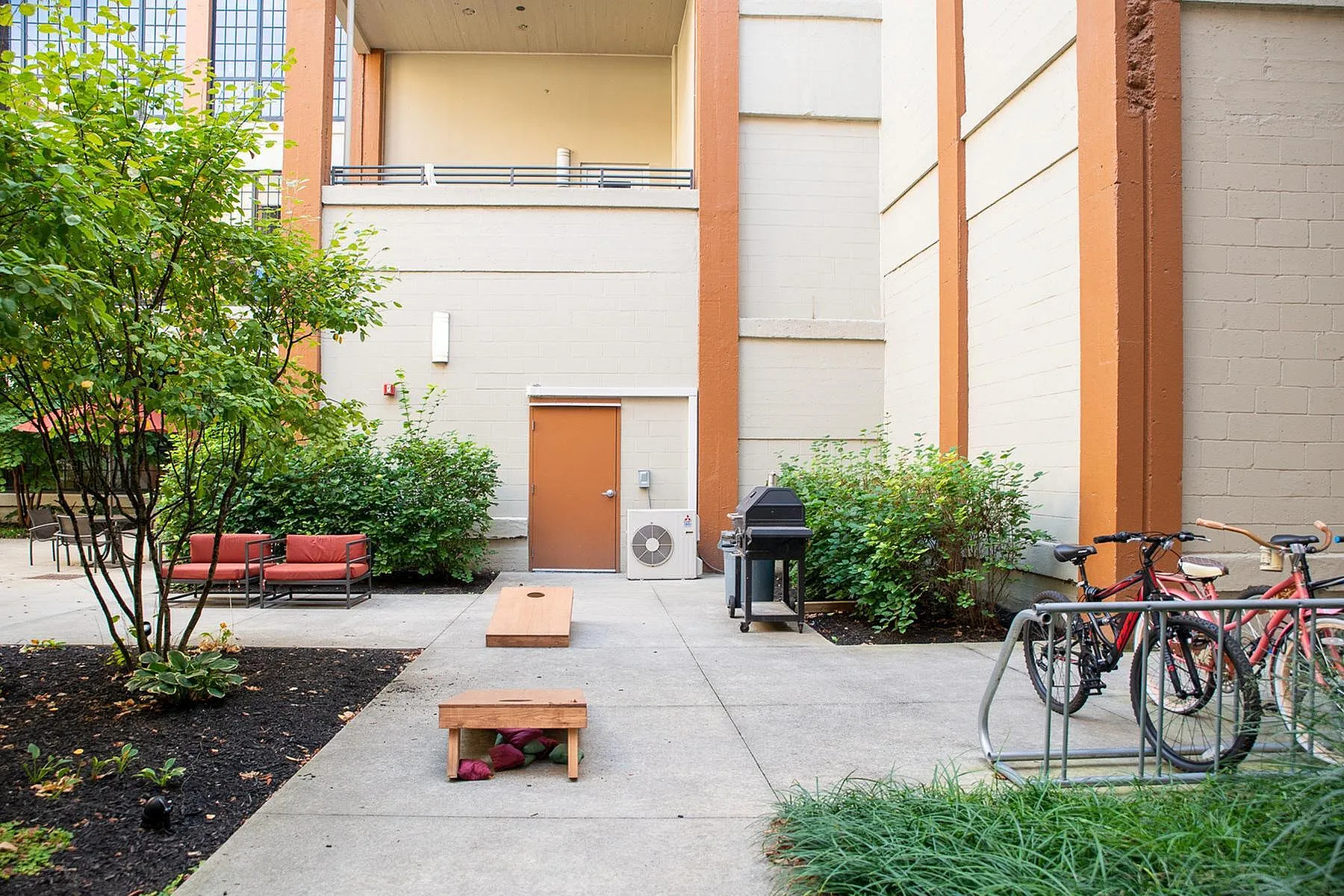 Charming outdoor patio with lounge chairs, lush greenery, and a barbecue grill, perfect for relaxation and entertainment.