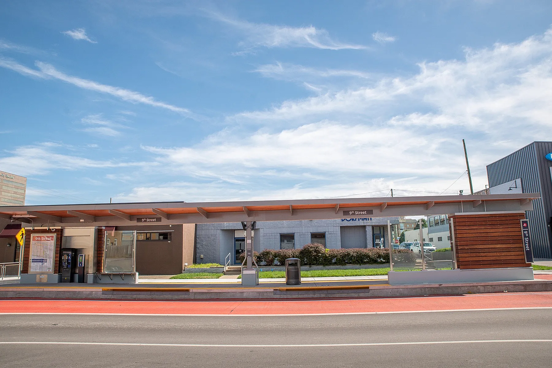 Chic urban bus station at 9th Street under a vibrant blue sky, featuring modern design and traveler-friendly amenities.