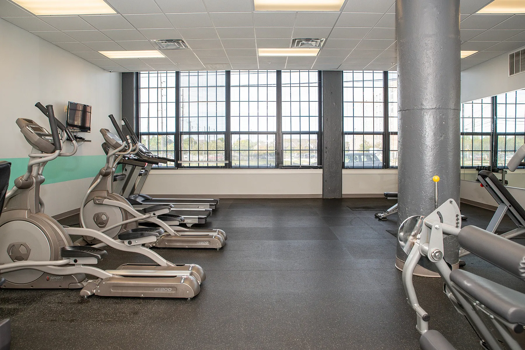 Modern fitness center with state-of-the-art cardio equipment and large windows offering abundant natural light.