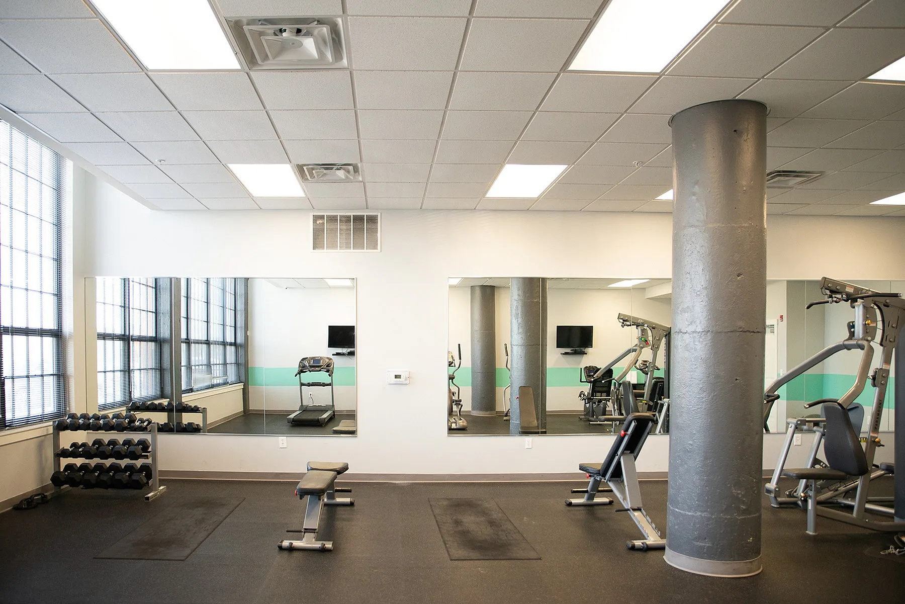 Bright, modern fitness center with mirrored walls, top-notch gym equipment, and ample natural light.