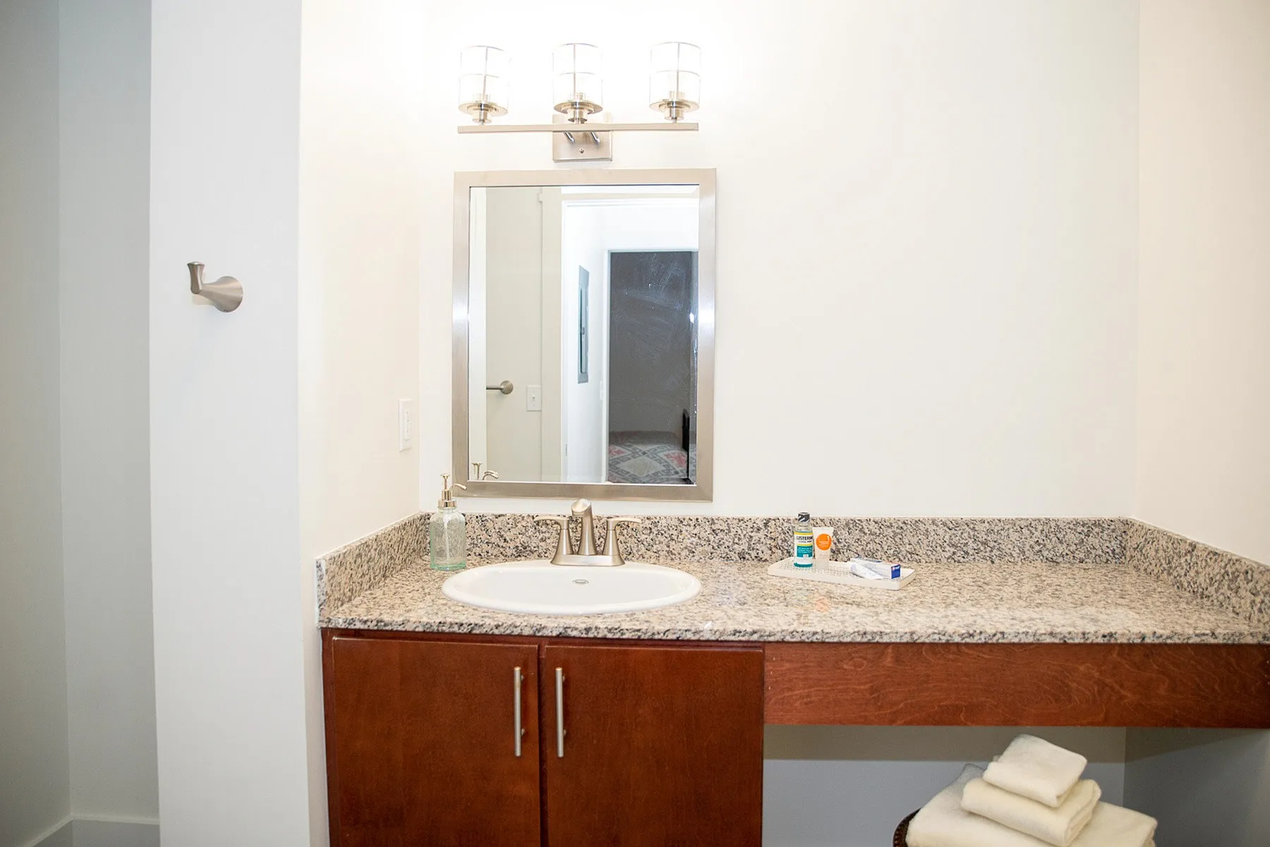 Bright and modern bathroom featuring a sleek granite countertop, elegant mirror, and warm lighting, creating a serene and inviting space.