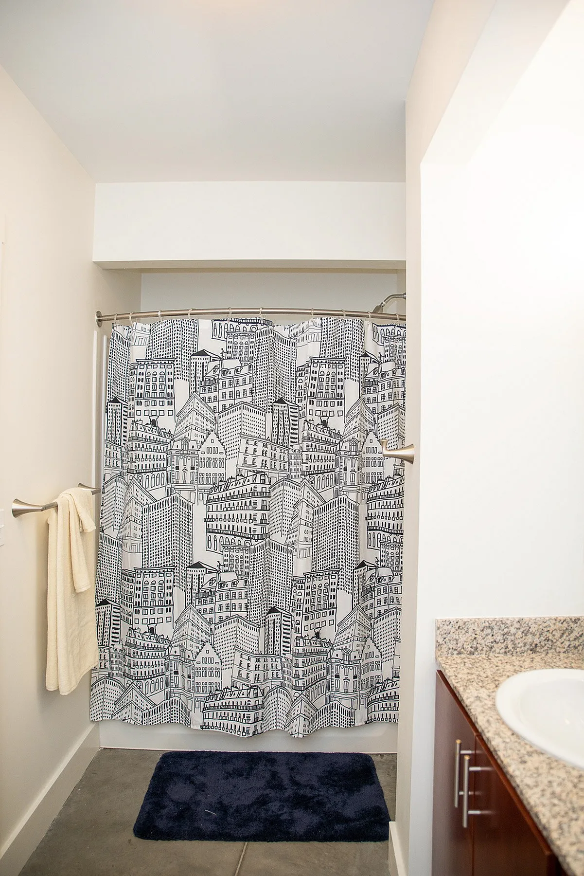 Chic bathroom with cityscape shower curtain, granite countertop, and modern fixtures.