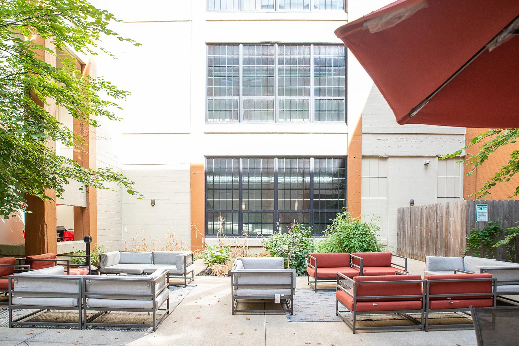 Charming outdoor courtyard with contemporary seating, surrounded by lush greenery and large windows.