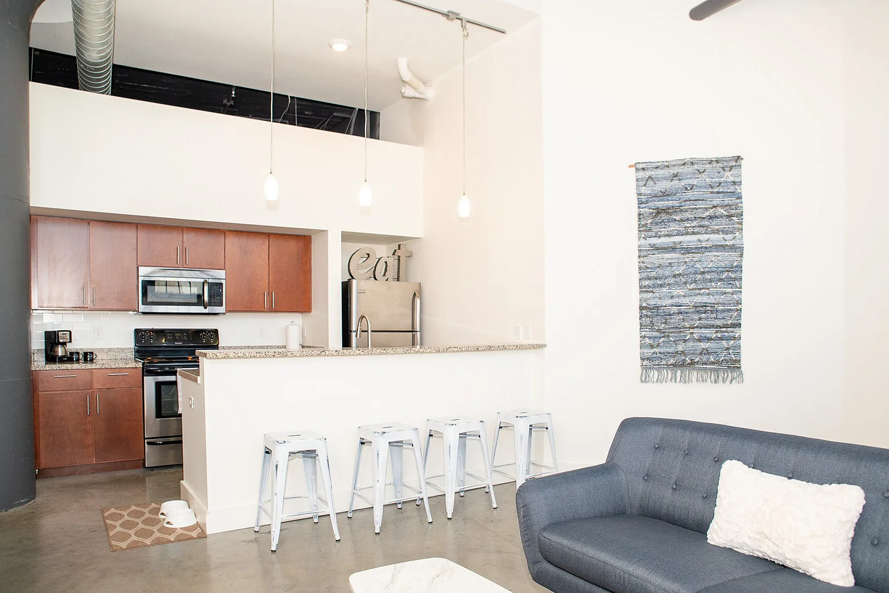Modern open-concept kitchen with granite countertops and stylish seating, adjacent to a cozy living area with elegant wall art.