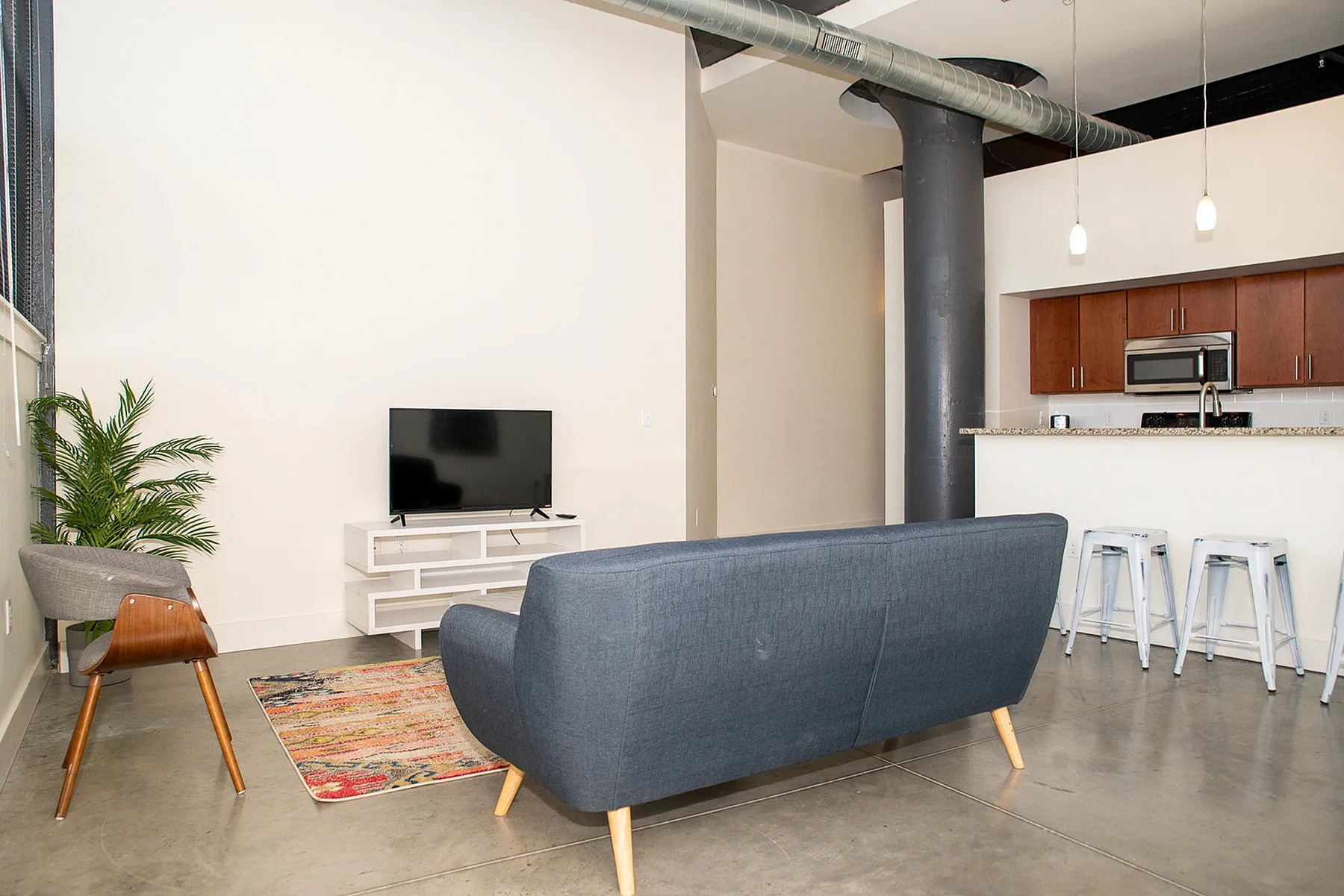 Modern open-concept living space with stylish seating, sleek kitchen, and chic industrial accents.