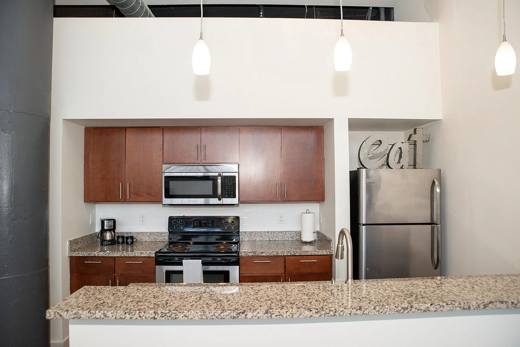 Contemporary kitchen showcasing sleek stainless steel appliances, elegant granite countertops, and modern cabinetry in a well-lit space.