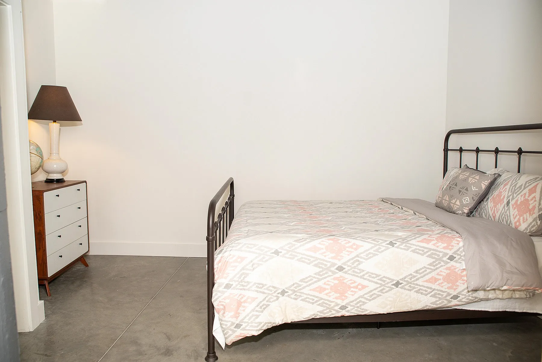 Cozy apartment bedroom with stylish iron bed, elegant lamp, and chic neutral decor.