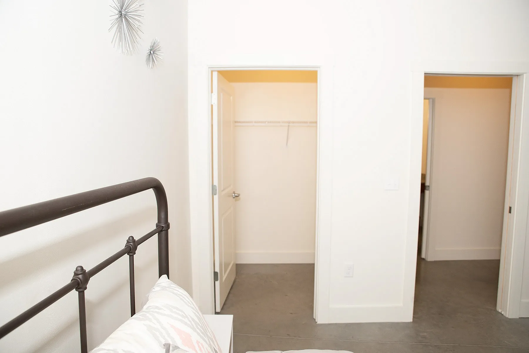 Bright and inviting bedroom featuring modern metal bed frame, neutral decor, and two spacious walk-in closets.