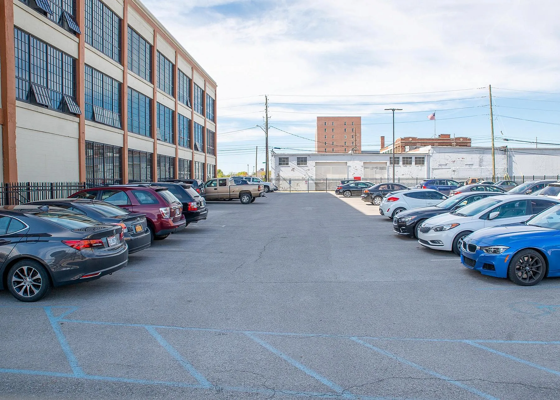 Spacious parking lot adjacent to a modern industrial-style building with abundant parking spaces under a clear blue sky.