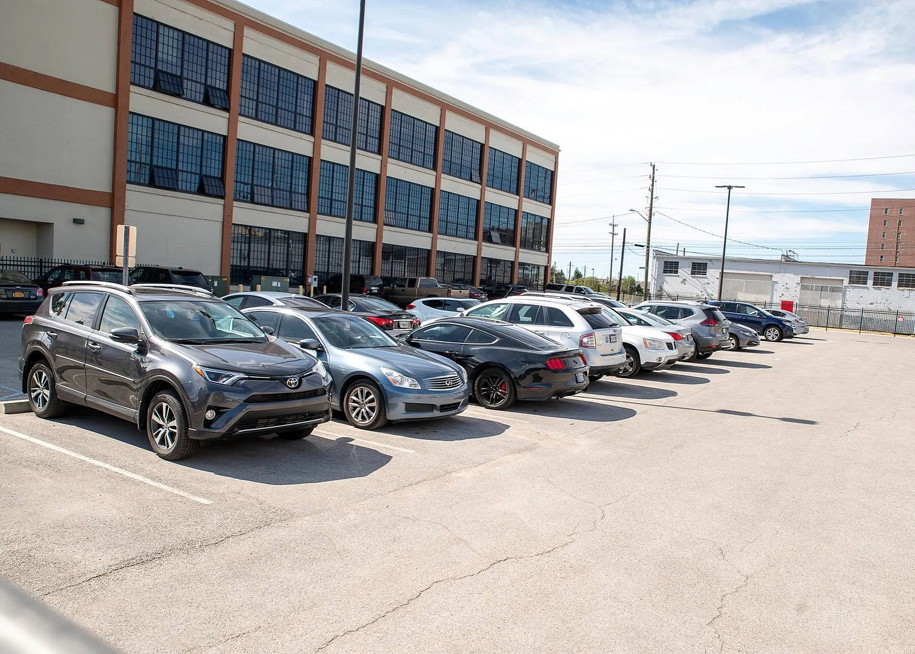 Spacious parking area in front of a modern building with large windows, featuring ample space for residents and guests.