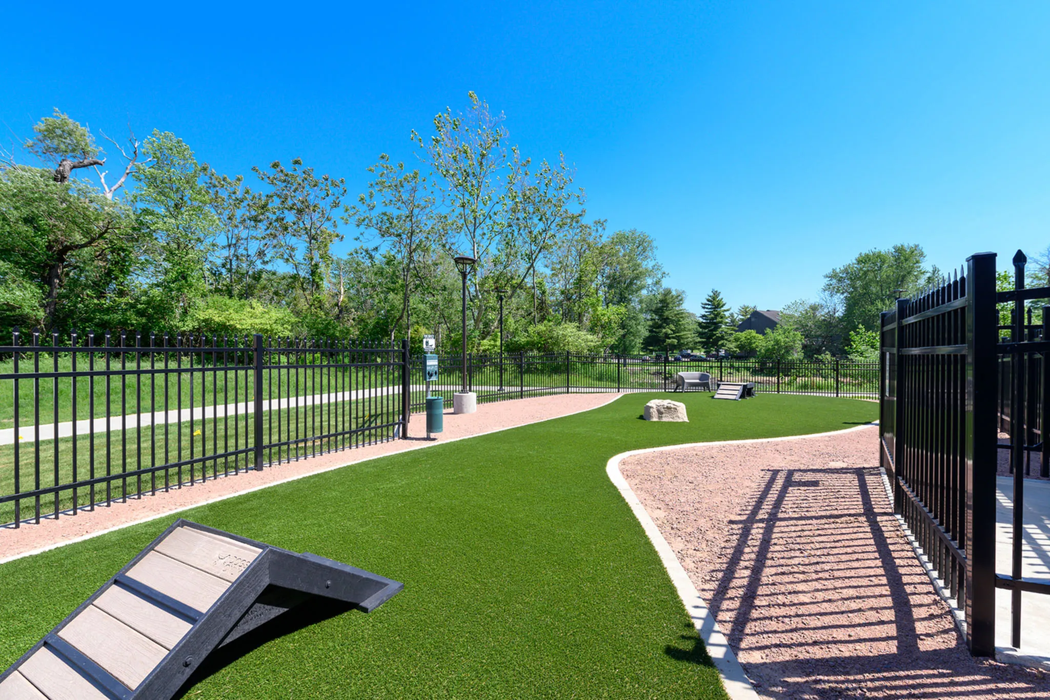Inviting outdoor space with lush green grass, perfect for pets, enclosed by elegant black fencing and surrounded by vibrant trees.