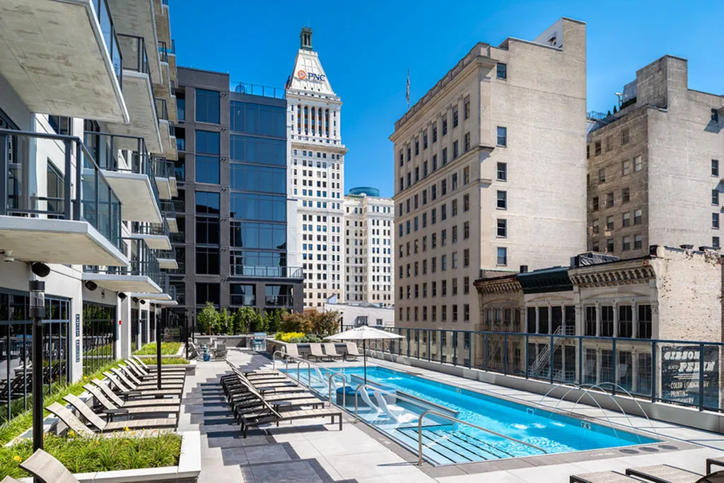Luxurious rooftop pool surrounded by modern high-rise buildings, offering stunning cityscape views and ample sunbathing space.