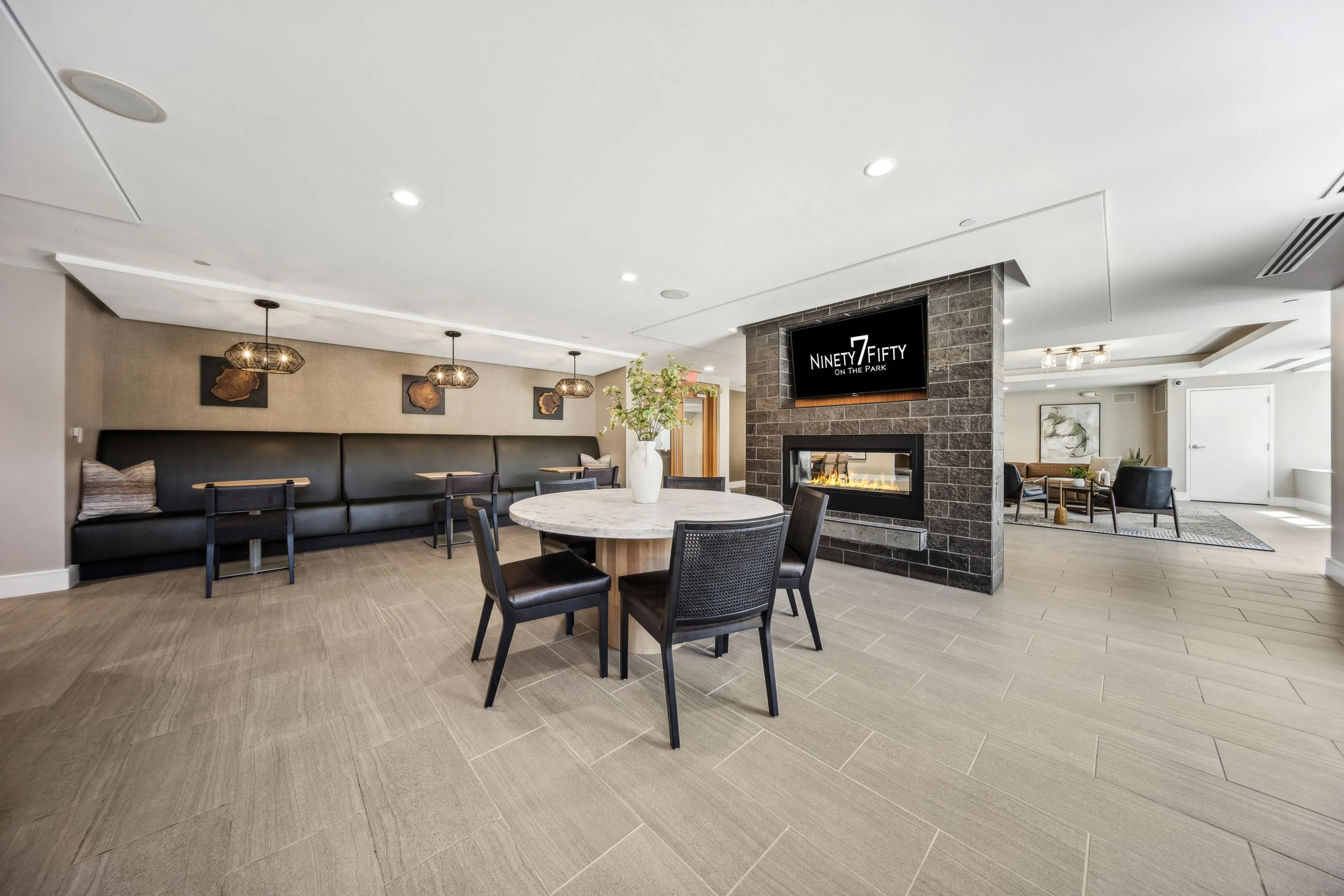Elegant communal space at Ninety7Fifty On The Park featuring cozy seating, stylish lighting, and a modern fireplace in a sophisticated lounge setting.