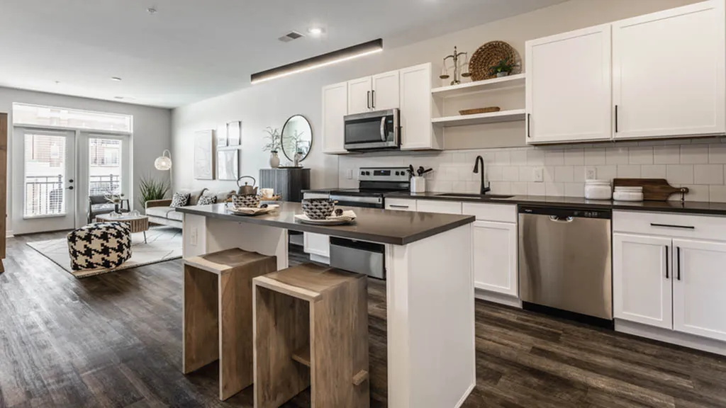 Modern open-concept apartment featuring a stylish kitchen with sleek stainless steel appliances, spacious living area with cozy seating, and elegant hardwood floors.