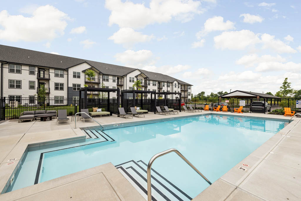 Chic apartment complex with luxurious outdoor pool, stylish lounge chairs, and modern facilities, perfect for relaxation and leisure.
